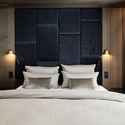 Komfortables Doppelbett im stilvollen Schlafzimmer des Lürzerhofs nahe Obertauern mit hochwertiger Holzverkleidung und elegantem Design