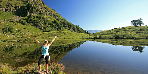 Eine Frau genießt die Natur an einem Bergsee während ihres Aktivurlaubs in Österreich