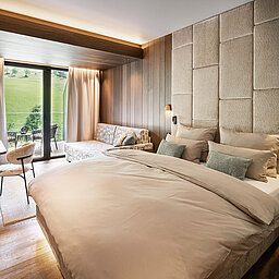 Modernes Doppelzimmer im Lürzerhof nahe Obertauern mit gemütlicher Sitzecke, Balkon und Blick auf die grüne Berglandschaft