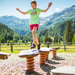 EIn Mädchen spielt auf einem Spielplatz des Alles Alm Erlebnisweges