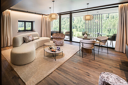 Großzügiger Wohnbereich einer Suite im Hotel Lürzerhof nahe Obertauern mit modernem Design und Panoramablick auf die Salzburger Bergwelt