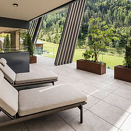 Großzügige Sonnenterrasse im Wellnesshotel Lürzerhof nahe Obertauern mit komfortablen Ruheliegen und Blick auf die grüne Salzburger Berglandschaft