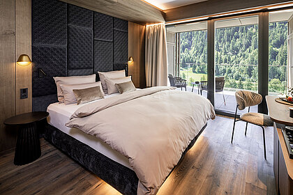 Elegantes Schlafzimmer im Lürzerhof nahe Obertauern mit Doppelbett, Panoramafenstern und Balkon mit Blick auf die Salzburger Bergwelt