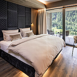 Elegantes Schlafzimmer im Lürzerhof nahe Obertauern mit Doppelbett, Panoramafenstern und Balkon mit Blick auf die Salzburger Bergwelt