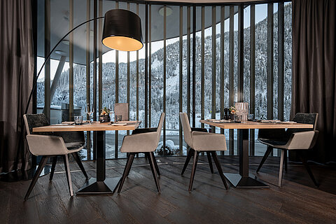 Ein stilvoll gedeckter Restaurantbereich im Lürzerhof Gourmet & Wellnesshotel mit Panoramablick auf die verschneite Berglandschaft.