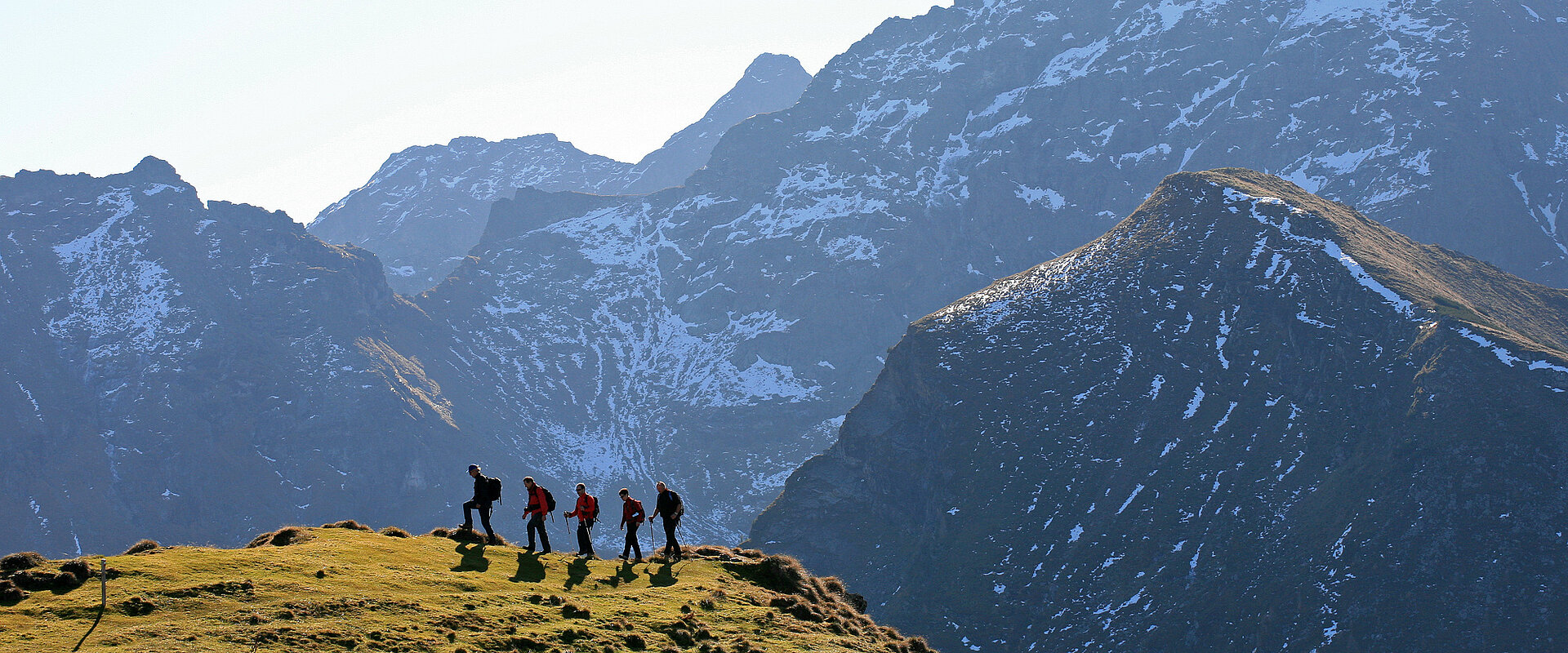 Eine Gruppe Wanderer genießt den Aktivurlaub in Österreich vor beeindruckender Bergkulisse.