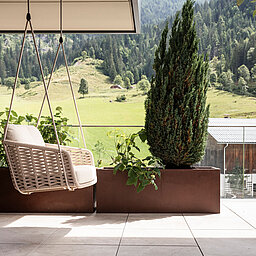 Gemütliche Hängeschaukel auf der Terrasse des Wellnesshotels Lürzerhof nahe Obertauern mit Blick auf die grüne Salzburger Bergwelt