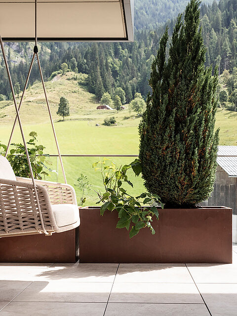 Gemütliche Hängeschaukel auf der Terrasse des Wellnesshotels Lürzerhof nahe Obertauern mit Blick auf die grüne Salzburger Bergwelt