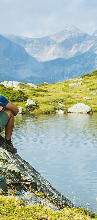 Zwei Wanderer sitzen auf Felsen am Bergsee in Obertauern