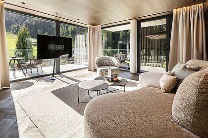Großzügige Hotelsuite mit Designsofa und Blick auf die Salzburger Bergwelt