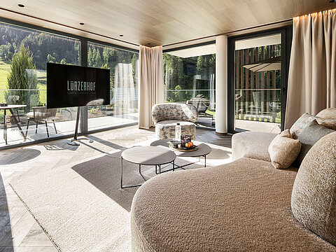 Großzügige Hotelsuite mit Designsofa und Blick auf die Salzburger Bergwelt