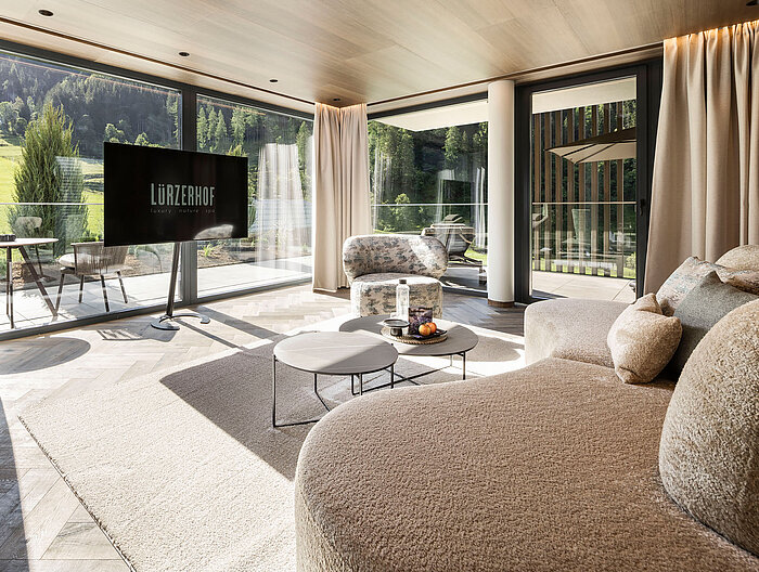 Großzügige Hotelsuite mit Designsofa und Blick auf die Salzburger Bergwelt