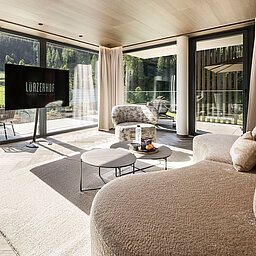 Großzügige Hotelsuite mit Designsofa und Blick auf die Salzburger Bergwelt