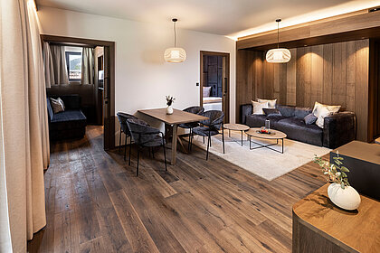Eleganter Wohn- und Essbereich einer Familiensuite im Lürzerhof nahe Obertauern mit hochwertiger Holzausstattung und gemütlicher Sitzecke