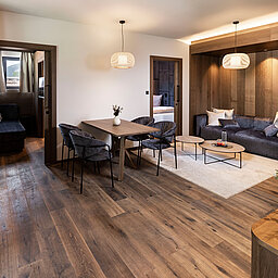 Eleganter Wohn- und Essbereich einer Familiensuite im Lürzerhof nahe Obertauern mit hochwertiger Holzausstattung und gemütlicher Sitzecke