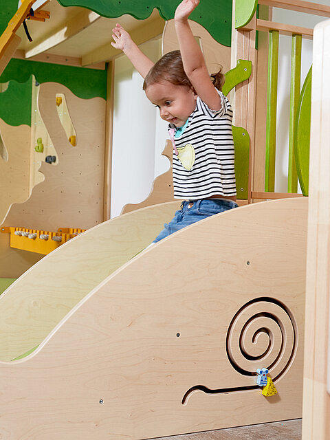 A girl sliding down a slide in the play area at the Lürzerhof, the family hotel in Austria for vacations with children.