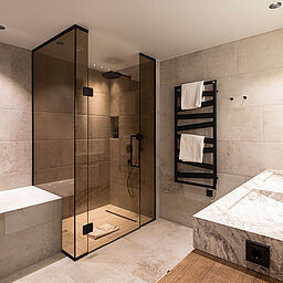 Luxuriöses Badezimmer einer Suite im Lürzerhof nahe Obertauern mit Badewanne, großer Regendusche und Doppelwaschtisch