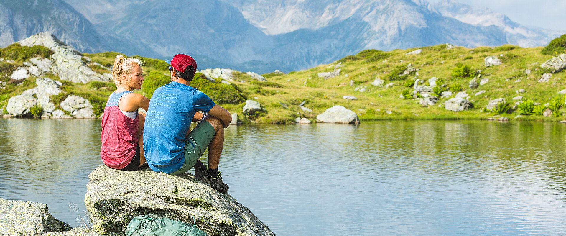 Zwei Wanderer sitzen auf Felsen am Bergsee in Obertauern