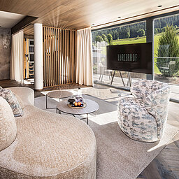 Wohnbereich der Suite 445 mit Panoramafenstern und Blick auf die Bergwiesen
