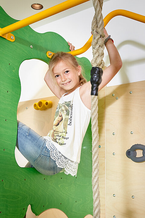 A girl climbs on a climbing frame in the play area of the Lürzerhof, the family hotel in Austria for vacations with children.