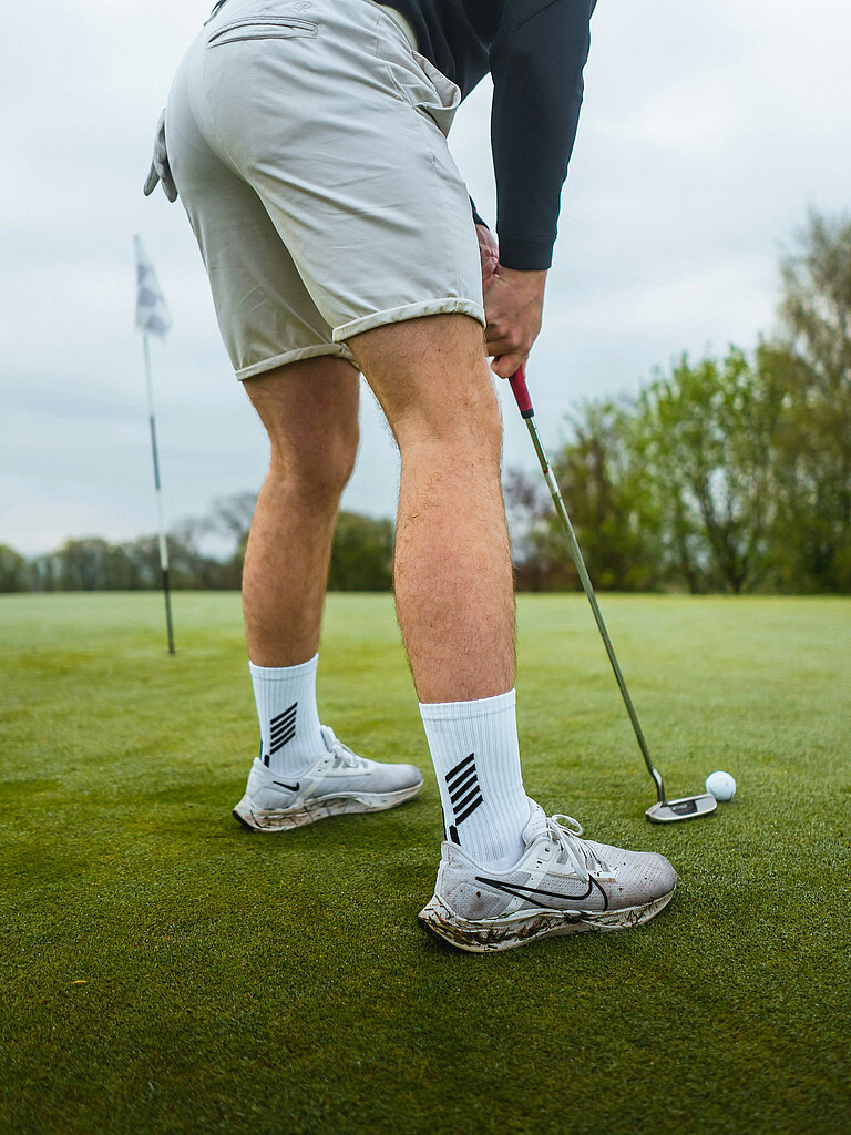 Golfer beim Putten mit Ball vor dem Loch auf dem Grün
