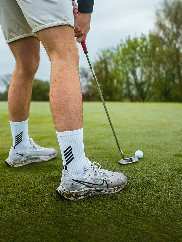 Golfer beim Putten mit Ball vor dem Loch auf dem Grün