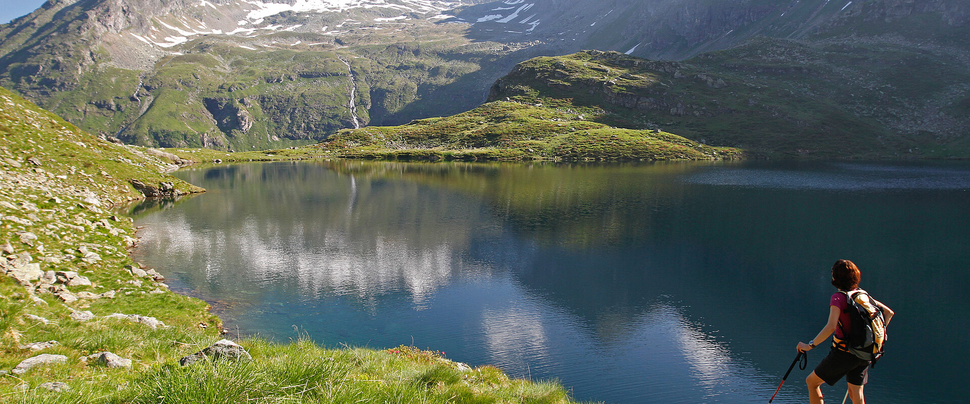 Eine Wanderin entspannt mit Blick auf den Bergsee während ihres Aktivurlaubs in Österreich