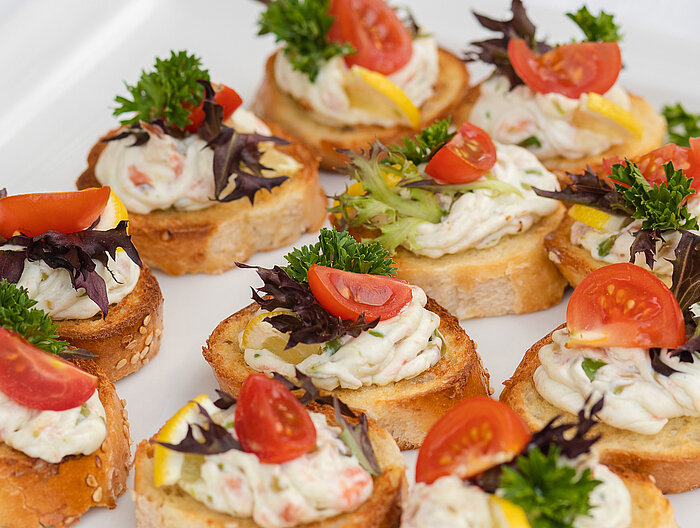 Canapés mit Creme, Tomate, Zitrone und Kräutern auf Weißbrot
