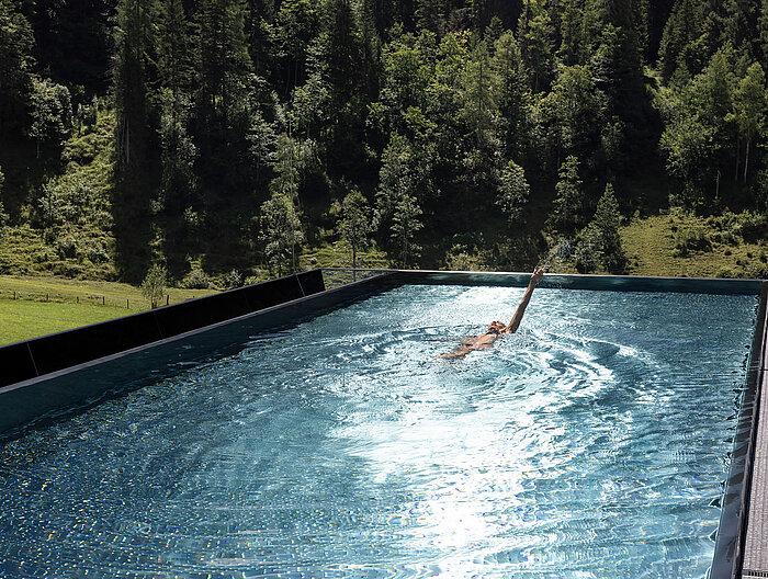 Schwimmen im Infinity Sky Pool des Lürzerhofs mit Blick auf Wald und Almwiesen nahe Obertauern
