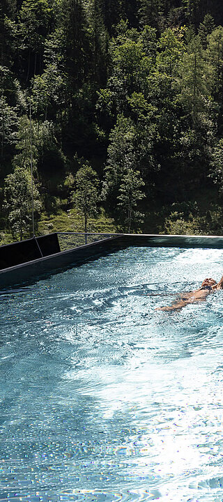 Schwimmen im Infinity Sky Pool des Lürzerhofs mit Blick auf Wald und Almwiesen nahe Obertauern