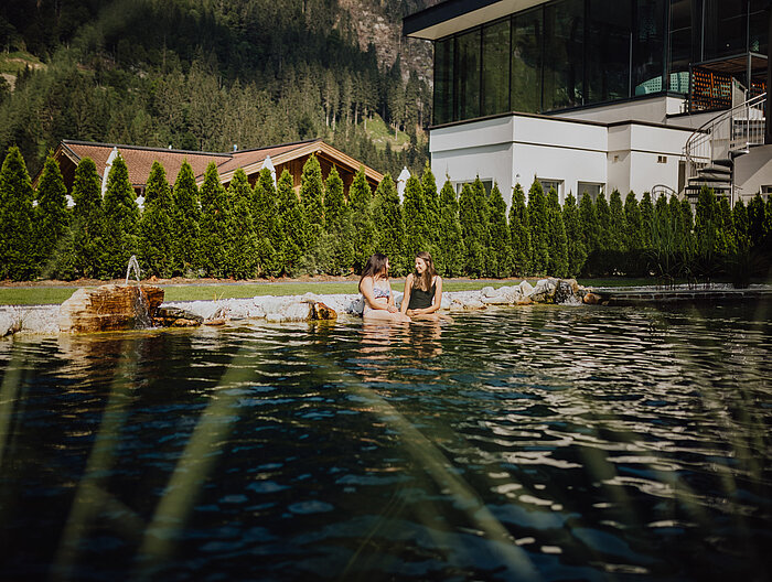 Gäste genießen die Zeit am Naturpool im Adults Only Bereich im Wellnesshotel Lürzerhof in Salzburg