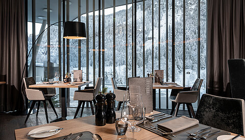 Ein stilvoll gedeckter Restaurantbereich im Lürzerhof Gourmet & Wellnesshotel mit Panoramablick auf die verschneite Berglandschaft.