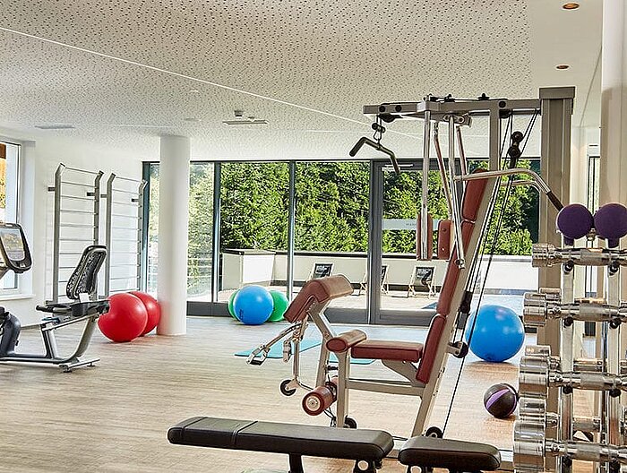 Moderner Fitnessraum mit Geräten und Hanteln im Tageslicht