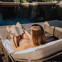 Eine Frau genießt die Sonne am Bergseepool im Lürzerhof Wellnesshotel in Salzburg