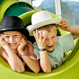 Zwei Kinder spielen auf einer Rutsche im Spielbereich des Lürzerhofs, dem Familienhotel in Österreich für Urlaub mit Kindern.