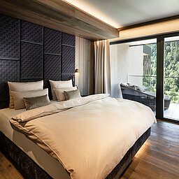 Hochwertiges Schlafzimmer einer Suite im Lürzerhof mit komfortablem Doppelbett, Balkon und Blick in die Natur nahe Obertauern
