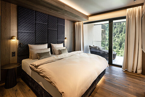 Hochwertiges Schlafzimmer einer Suite im Lürzerhof mit komfortablem Doppelbett, Balkon und Blick in die Natur nahe Obertauern