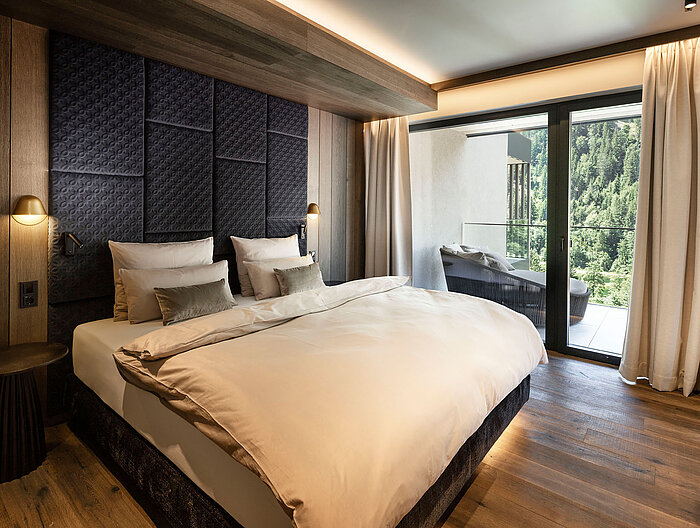 Hochwertiges Schlafzimmer einer Suite im Lürzerhof mit komfortablem Doppelbett, Balkon und Blick in die Natur nahe Obertauern