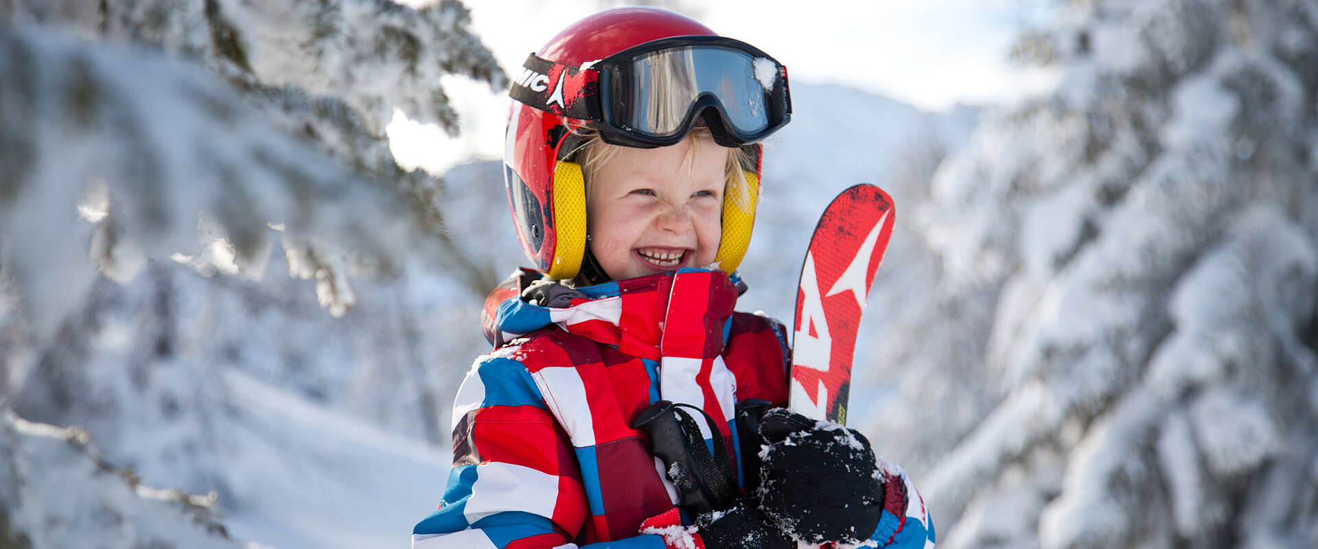Kind mit Ski in der Hand im Skiurlaub in Obertauern