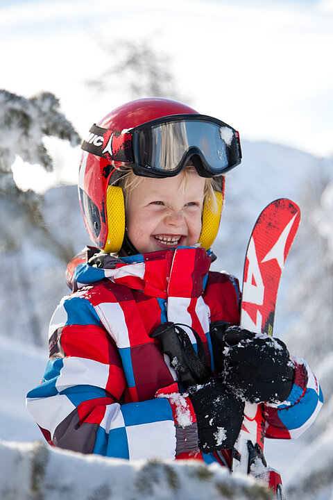 Kind mit Ski in der Hand im Skiurlaub in Obertauern