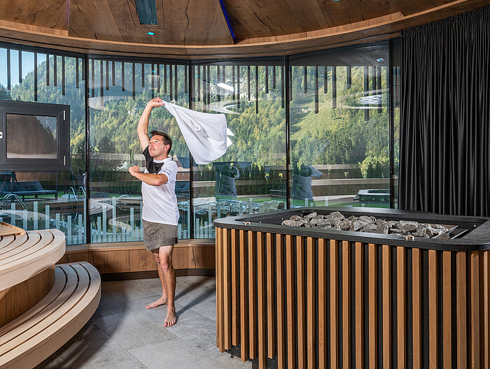 Ein Mann macht einen Sauna Aufguss im Wellnesshotel Lürzerhof in Salzburg