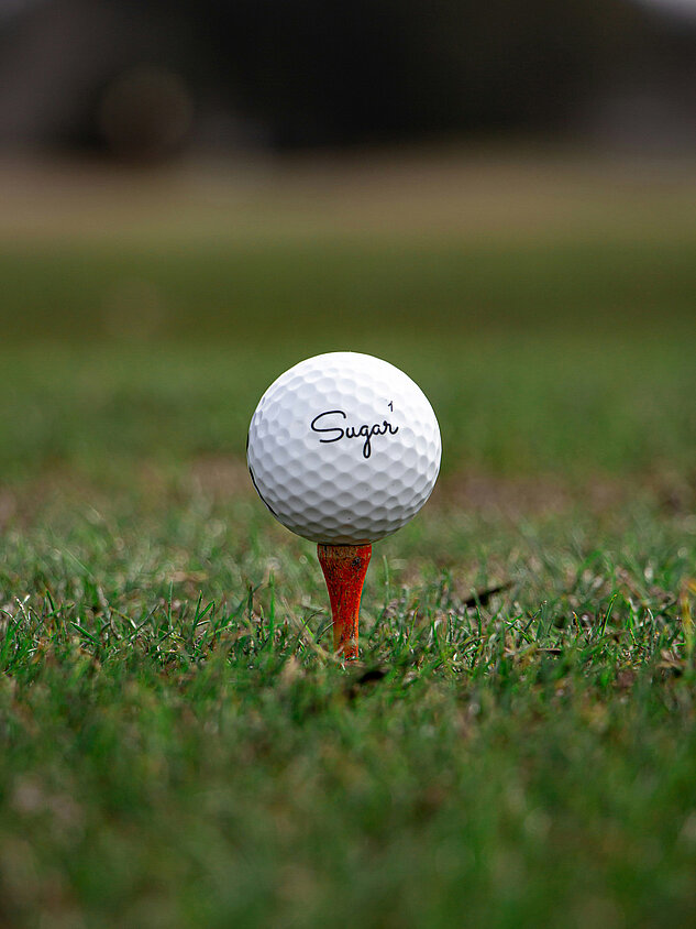 Golfball auf rotem Tee auf einer Golfwiese