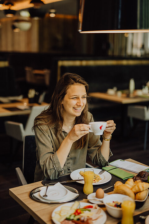 Eine Frau genießt das Frühstück im Gourmet & Wellnesshotel Lürzerhof