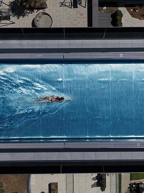 Schwimmerin im großzügigen Infinity Sky Pool des Wellnesshotels Lürzerhof nahe Obertauern aus der Vogelperspektive