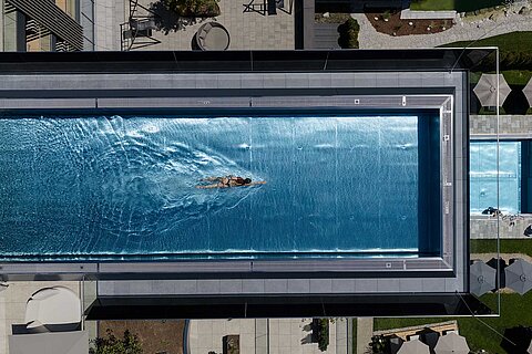 Schwimmerin im großzügigen Infinity Sky Pool des Wellnesshotels Lürzerhof nahe Obertauern aus der Vogelperspektive