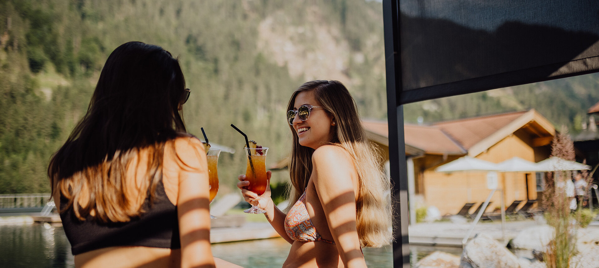 Zwei Frauen genießen die Sonne am Bergseepool im Lürzerhof Wellnesshotel in Salzburg