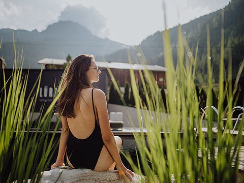 Eine Frau sitzt am Naturpool im Adults Only Bereich im Wellnesshotel Lürzerhof in Salzburg