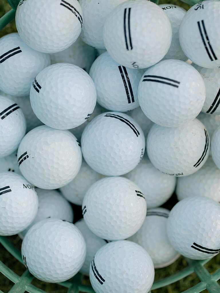 Korb mit vielen weißen Golfbällen mit schwarzen Markierungen
