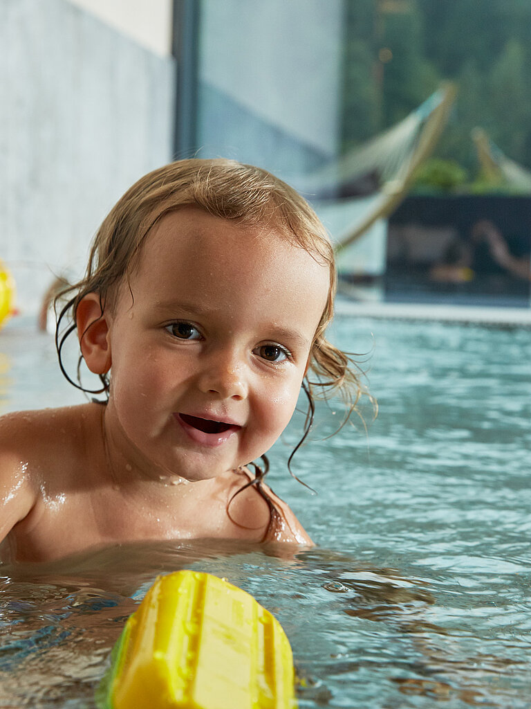 Ein Kleinkind spielt im Indoorpool im Wellnesshotel Lürzerhof in Salzburg