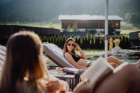Eine Frau genießt die Sonne am Bergseepool im Lürzerhof Wellnesshotel in Salzburg